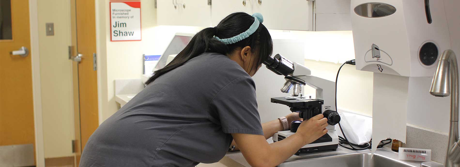 Veterinary Assistant at the Veterinary Center looks at Microscope